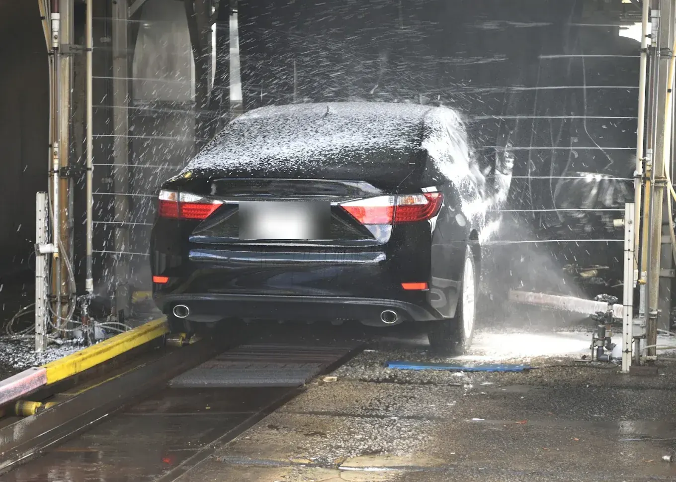 Black Toyota Camry being washed in the car wash bay at Madeena Al Amwaj Auto Workshop