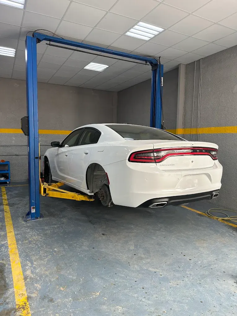 White Dodge Charger on the lift for wheel and brake service at Madeena Al Amwaj Auto Workshop