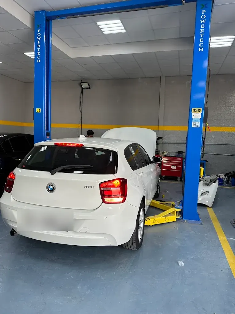 White BMW 1 Series on the lift for mechanical service at Madeena Al Amwaj Auto Workshop
